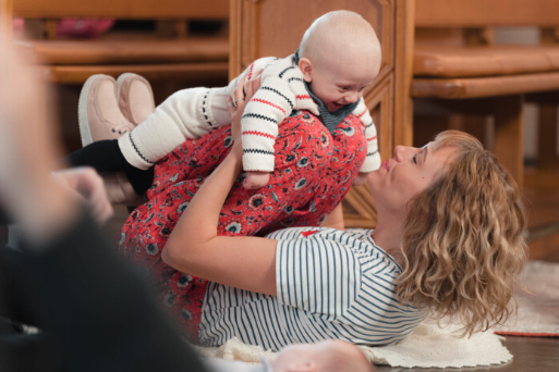 Mor og baby tumler og hygger på gulvet til babysalmesang.