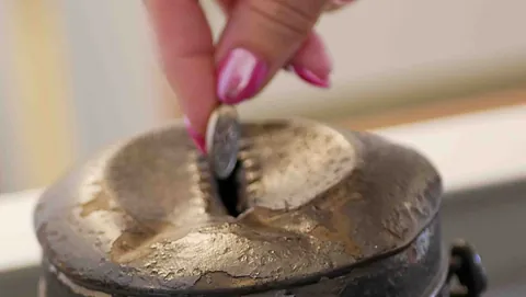 En kvinde donerer en mønt til kirkens indsamling.