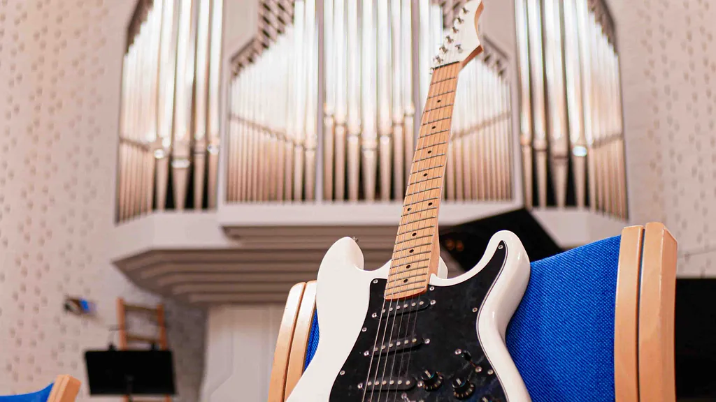 Rytmiske gudstjenster i udlejre kirke. En hvid elektrisk guitar foran orglet i udlejre kirke. 