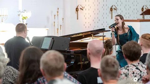 Koncert i Udlejre kirke i Ølstykke. En sanger og en pianist spiller musik foran stort publikum.